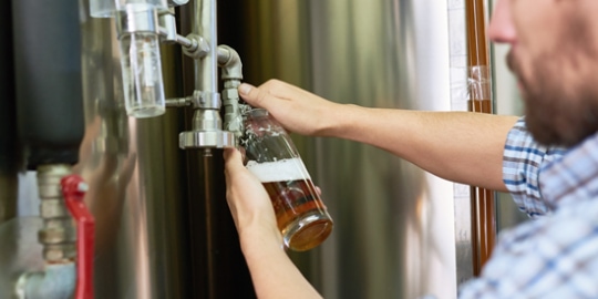 brewer pouring beer into bottle direct from brewing process