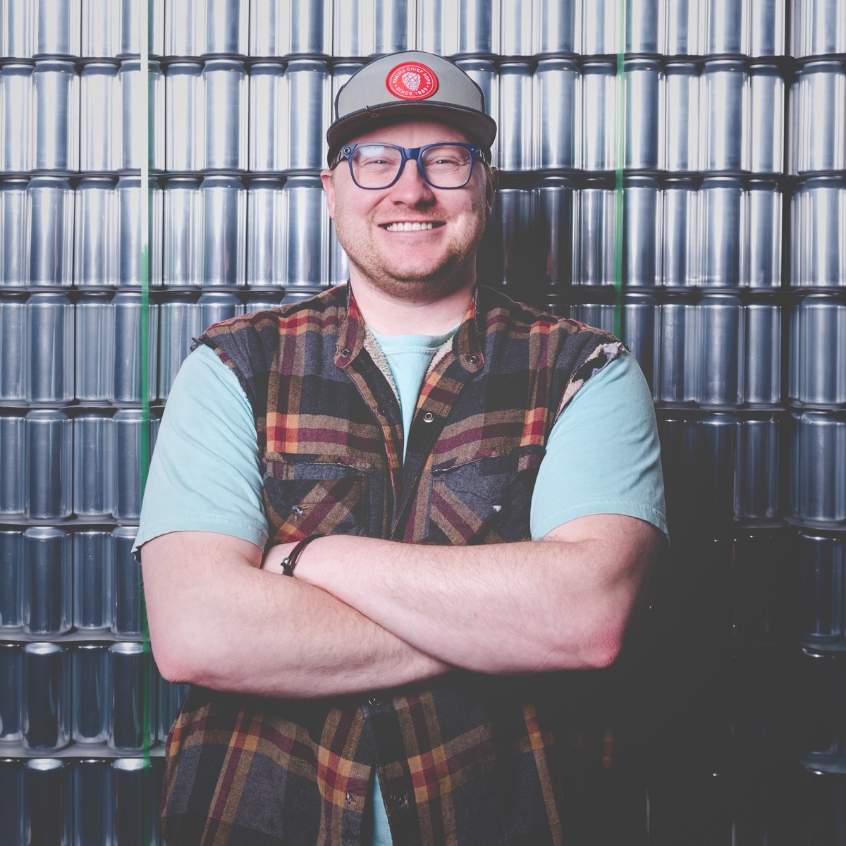 Josh Eagy, man with blue-rimmed glasses with flannel vest and hat